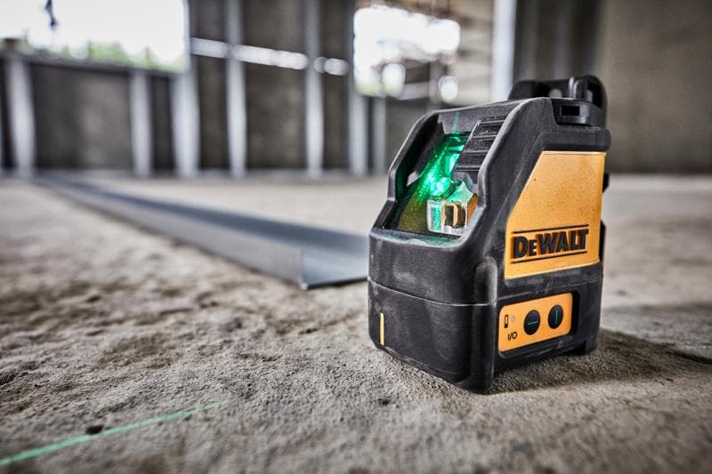 DEWALT green beam laser level DW088CG placed on a concrete floor inside a construction site.