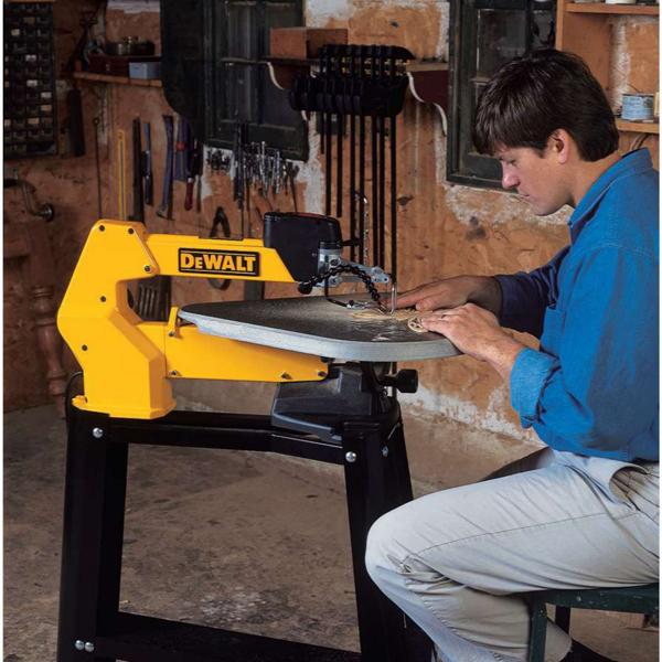 A person using a DEWALT scroll saw in a workshop, with various tools hanging on the wall in the background. The person's face is blurred for privacy.